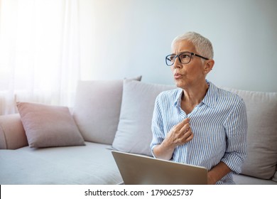 Mature Woman Experiencing Hot Flush From Menopause. Tired Mature Woman Tolerating Hot Flash. Hot Flashes. Exhausted Mature Woman Resting On Sofa And Having Hot Flash