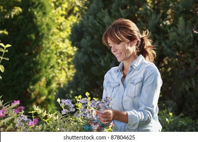 Mature Woman Gardening In Her Backyard