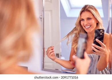 Mature Woman Getting Ready In Bathroom At Home Posing For Selfie On Mobile Phone