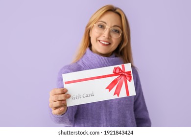 Mature Woman With Gift Card On Color Background