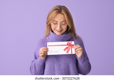 Mature Woman With Gift Card On Color Background