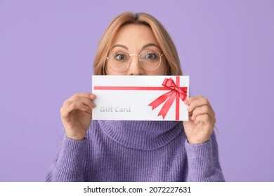 Mature Woman With Gift Card On Color Background