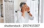 Mature woman, glasses and shopping in mirror with choice, optometry and smile with healthy vision. Person, client and customer with decision for prescription eyewear, change or fitting frame at store