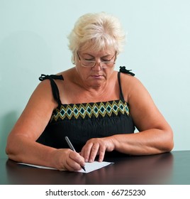 Mature Woman With Glasses Writing A Letter.