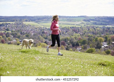 Mature Woman With Golden Retriever Jogging In Countryside