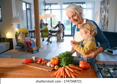 Mature woman and granddaughter preparing food in kitchen for family - Powered by Shutterstock