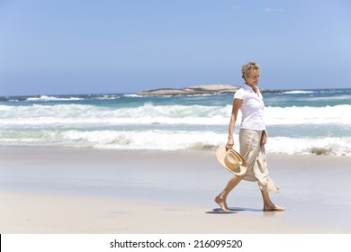 Mature Woman With Hat Walking On Beach