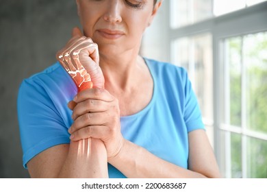 Mature woman having pain in wrist at home - Shutterstock ID 2200683687
