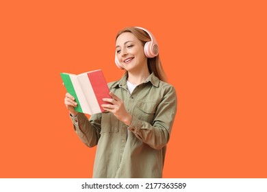 Mature Woman With Headphones Reading Book On Orange Background. Concept Of Studying Italian Language