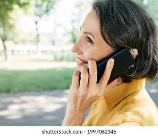 Mature woman with hearing aid has a full life and can hear interlocutor on phone. Hearing solution and innovation technology