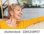 Mature woman with hearing aid indoors smiling