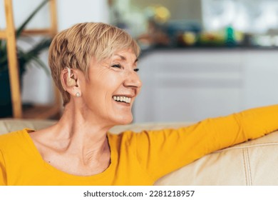 Mature woman with hearing aid indoors smiling - Shutterstock ID 2281218957
