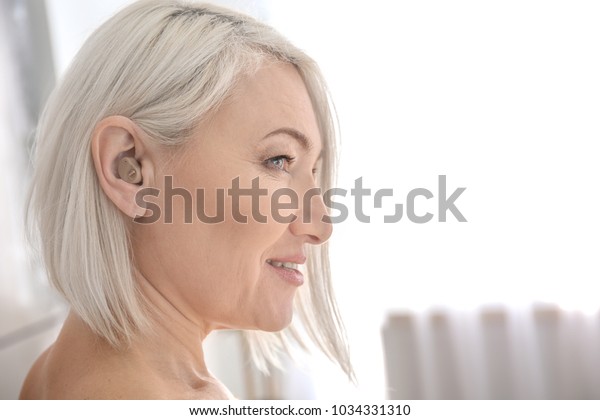 Mature woman with hearing\
aid indoors