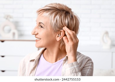 Mature woman with hearing aid in room - Powered by Shutterstock