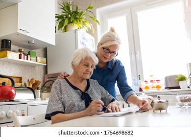 Mature Woman Helping Elderly Mother With Paperwork
