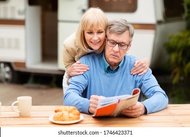 Mature Woman Helping Her Husband Solve Crossword Puzzle Near Trailer Outside