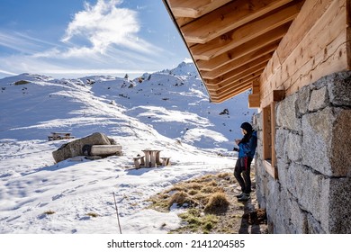 Mature Woman Hiker Chats With Smartphone In Front Of The Hut In The Snow