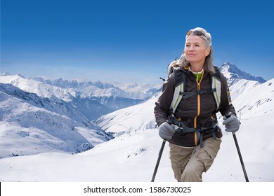 Mature Woman Hiking Through Snow Covered Mountains