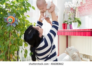 Mature Woman Holding Up Baby Granddaughter In Kitchen