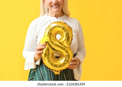 Mature Woman Holding Balloon And Flower On Yellow Background. International Women's Day Celebration