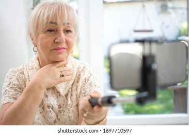 Mature Woman Holding Selfie Stick With Smart Phone While Having A Video Call At Home