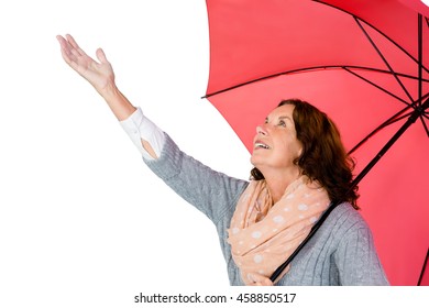 Mature woman holding umbrella while standing against white background - Powered by Shutterstock