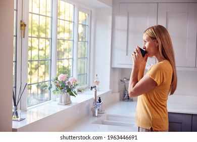 Mature Woman At Home With Hot Drink Standing By Kitchen Window - Powered by Shutterstock