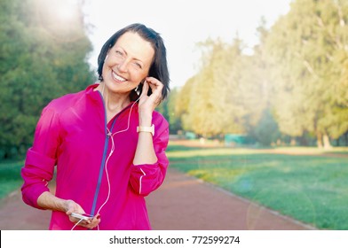 Mature woman listen music before or after jog in the park. Attractive looking mature woman keeping fit and healthy - Powered by Shutterstock