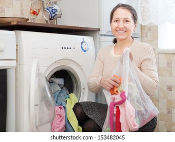 Mature Woman Loading The Washing Machine With Laundry Bag