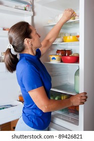 Mature Woman Looking For Something In The Fridge At Home