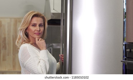 Mature Woman Looking Thoughtfully Into The Fridge Picking Food