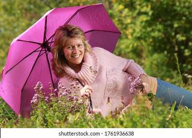 Mature woman lying in grass with umbrella