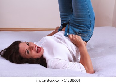 Mature Woman Lying On The Bed Trying To Pull A Pair Of Jeans / Favorite Pants Too Tight