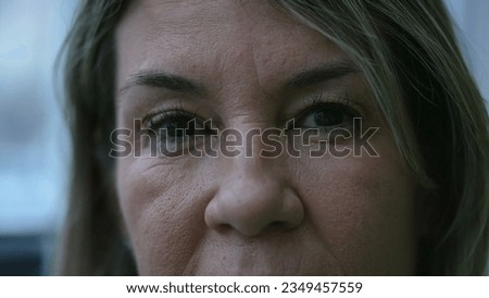 Mature woman macro close-up eyes staring at camera with serious expression. 50s female caucasian person portrait