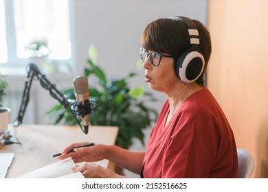 Mature Woman Making Podcast Recording For Her Online Show. Attractive Business Woman Using Headphones Front Of Microphone For A Radio Broadcast