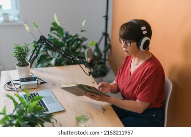 Mature Woman Making Podcast Recording For Her Online Show. Attractive Business Woman Using Headphones Front Of Microphone For A Radio Broadcast