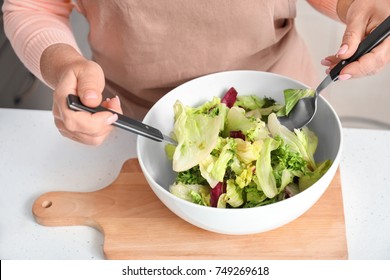 Mature Woman Making Salad In Kitchen