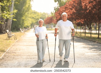 Mature woman and man training with walking poles in park - Powered by Shutterstock