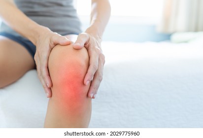 Mature woman massaging painful knee, joint inflammation arthritis problems. Woman suffering from knee pain at home, closeup. 