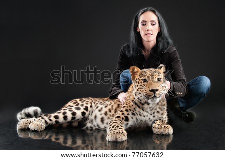 Mature woman near to spotty leopard, on studio.