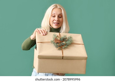 Mature Woman Opening Christmas Gift Box On Color Background