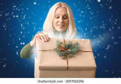 Mature Woman Opening Christmas Gift On Color Background