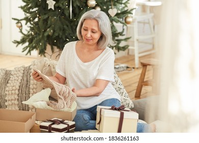 Mature Woman Opening Christmas Present And Getting The Warm Scarf Out Of The Box