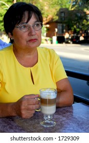 Mature Woman In Outdoor Cafe With Coffee Looking Sad