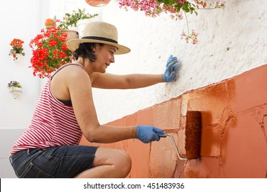 mature woman painting the backyard  in old  mud house