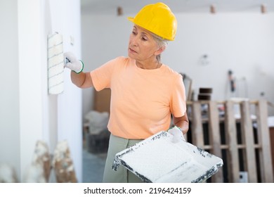 Mature Woman Painting Interior Wall With Paint Roller During Overhaul, Enjoying Home Renovation