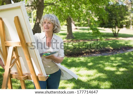 Mature woman painting on canvas in the park