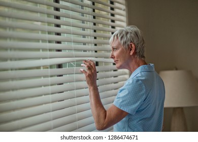 Mature woman peeks at her neighbors through the blinds. - Powered by Shutterstock