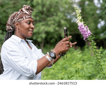 Mature woman photographing flowers in garden - Powered by Shutterstock