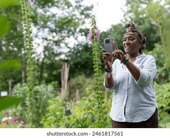 Mature woman photographing flowers in garden - Powered by Shutterstock